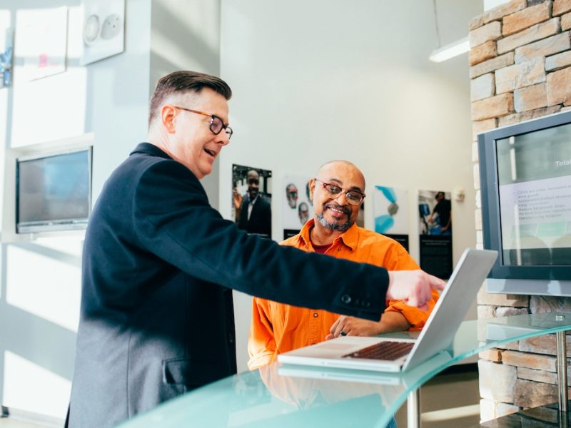 Two colleagues smiling while looking at a laptop in an office