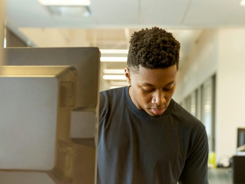 Man writing notes at his desk next to a computer