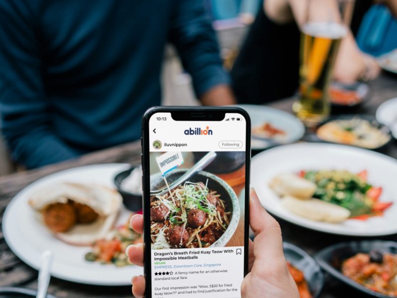 Diner holding a phone over plates of food at a restaurant table