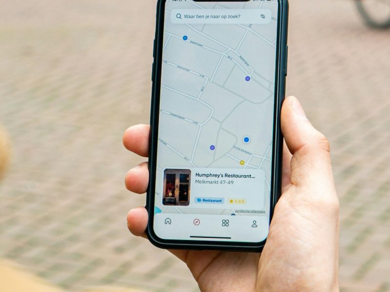 Person on a high street holding a phone showing Google Maps