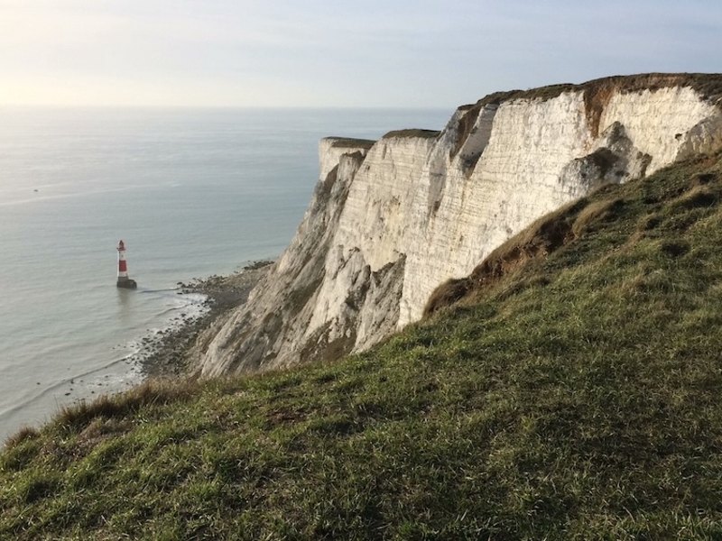 Chalk cliffs above the sea with a striped lighthouse below