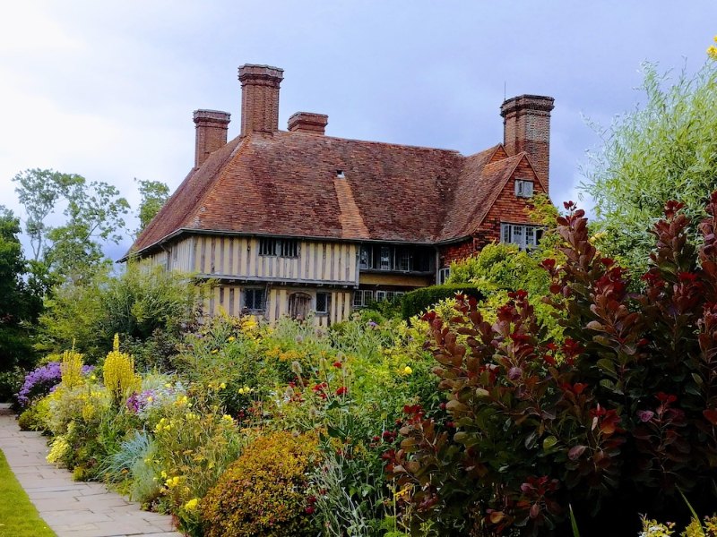 Tudor house with tall brick chimneys behind a colourful garden