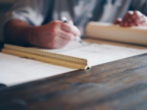 Person writing a checklist on paper at a wooden desk