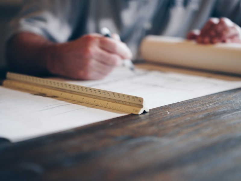 Person writing a checklist on paper at a wooden desk