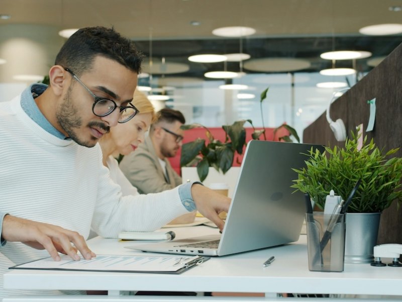 Colleagues working on laptops at a long shared office desk