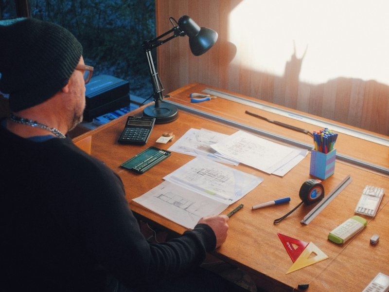 Man in a cap working at a wooden workbench with tools