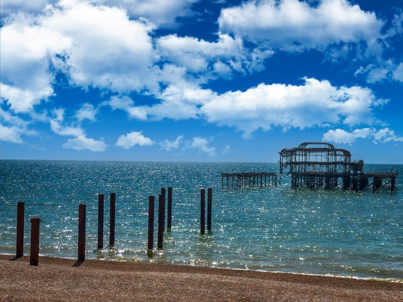 Ruins of an old pier standing in the sea beyond a row of wooden posts